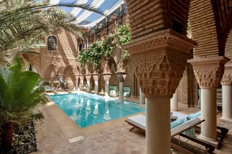 A tranquil pool nestled in an indoor courtyard, framed by stunning arches and pillars, perfect for Morocco holiday deals.