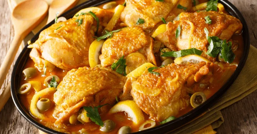 A vibrant Moroccan dish featuring chicken, vegetables, and olives beautifully arranged in a pan.